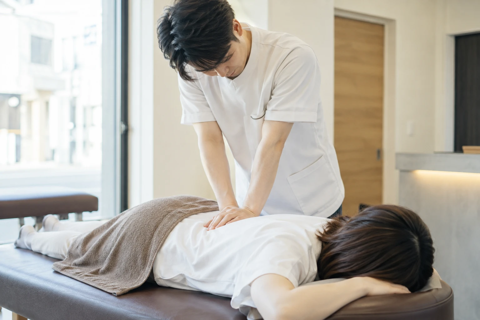 明るい整体院で、お客様に施術するスタッフ